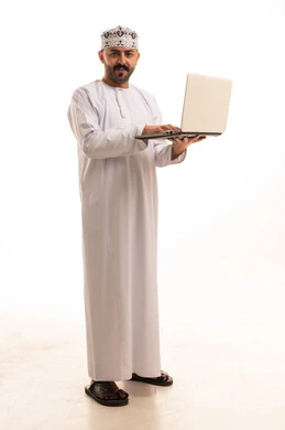 رجل عُماني بالزي التقليدي يستخدم الحاسوب المحمول