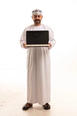 رجل عُماني يحمل جهاز لابتوب بخلفية بيضاء