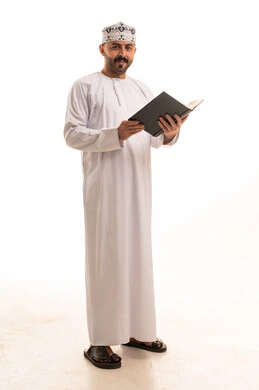رجل عُماني بالزي التقليدي يمسك كتاباً