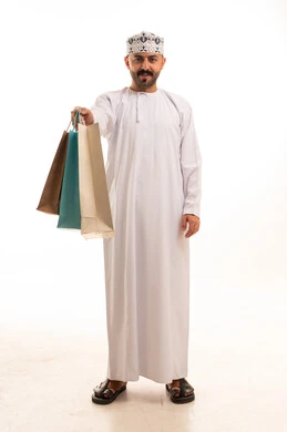 رجل عماني بالزي التقليدي يحمل حقائب تسوق