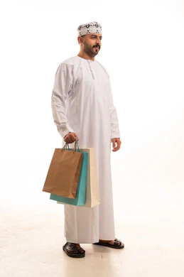 رجل عماني بالزي التقليدي يحمل أكياس تسوق