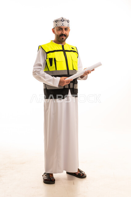 مهندس عُماني بزي السلامة يحمل مخططاً هندسياً