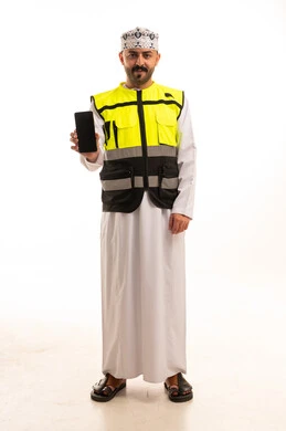 رجل عماني يرتدي سترة سلامة ويمسك هاتف ذكي