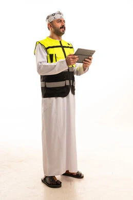 مهندس عماني يرتدي سترة سلامة ويمسك بجهاز لوحي