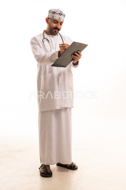 طبيب عماني بالزي التقليدي يكتب على لوحة ملاحظات