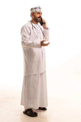 Omani Doctor Talking on Smartphone in White Studio