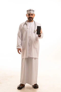 طبيب عماني يحمل هاتفاً ذكياً بخلفية بيضاء