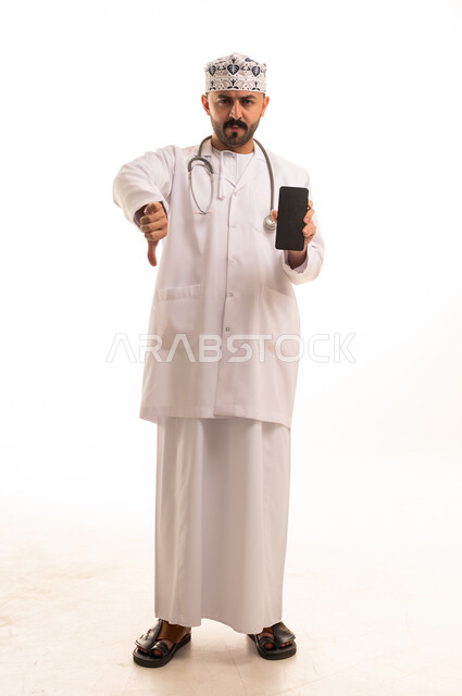 طبيب عماني يحمل هاتفا ذكيا مع إشارة الرفض