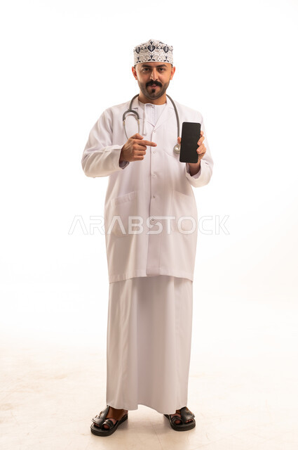 طبيب عماني يحمل هاتف ذكي بالزي الطبي