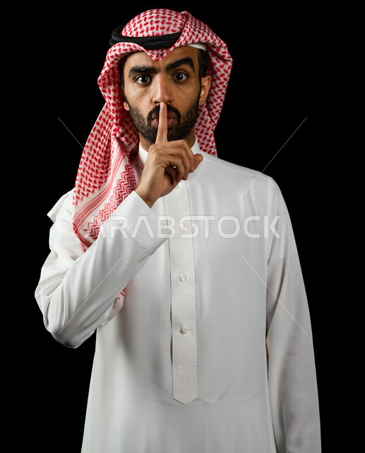 رجل عربي سعودي خليجي يرتدي الزي السعودي, إيماءات يدين تدل على طلب الهدوء, عدم الإزعاج, التوقف عن الكلام, الأمر بالصمت والسكوت, خلفيه سوداء