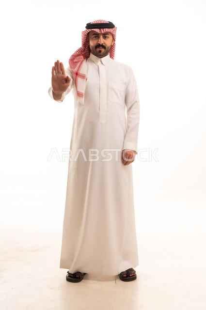 رجل سعودي يشير بحركة توقف بالزي التقليدي