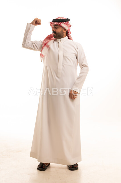 رجل سعودي بالثوب التقليدي يستعرض عضلات ذراعه