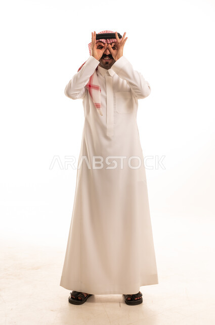 رجل سعودي بالثوب التقليدي يشكل منظاراً بيديه
