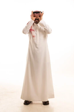 رجل سعودي بالثوب التقليدي يشكل منظاراً بيديه
