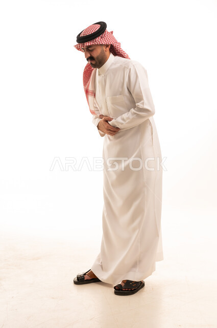 رجل سعودي يعاني من ألم في البطن بالزي التقليدي استوديو