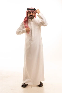 رجل سعودي بالزي التقليدي يقف أمام خلفية بيضاء