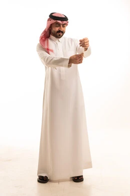 رجل سعودي بالثوب الأبيض التقليدي يقوم بتعديل أكمامه