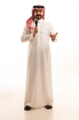 رجل سعودي بالزي التقليدي يمسك ميكروفون للتحدث