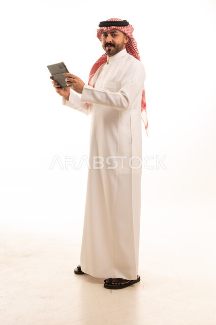 رجل سعودي بالزي التقليدي مع جهاز لوحي