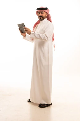 رجل سعودي بالزي التقليدي مع جهاز لوحي