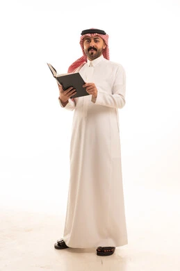 رجل سعودي بالزي التقليدي يقرأ كتاباً في الاستوديو