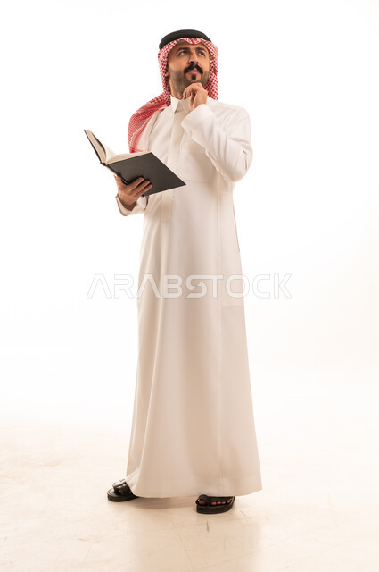رجل سعودي بالزي التقليدي يقرأ كتاباً بخلفية بيضاء