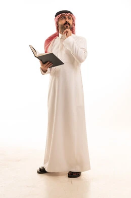 Saudi Man in Traditional White Thobe Reading a Book