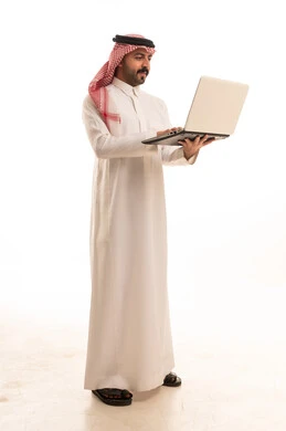 رجل سعودي بالزي التقليدي يستخدم الحاسوب المحمول