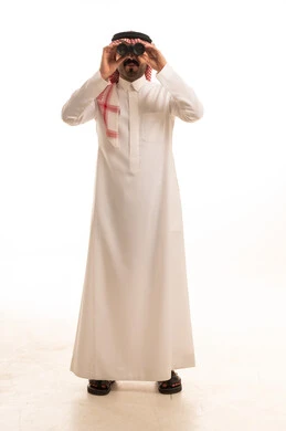 رجل سعودي بالزي التقليدي يستخدم المنظار في الاستوديو