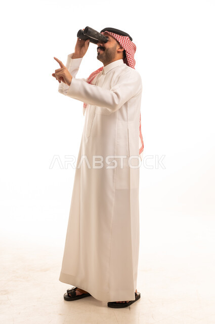 رجل سعودي بالزي التقليدي يستخدم المنظار