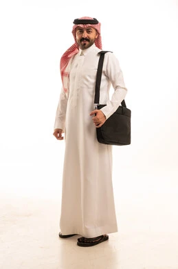 رجل سعودي بالثوب التقليدي يحمل حقيبة عمل في الاستوديو