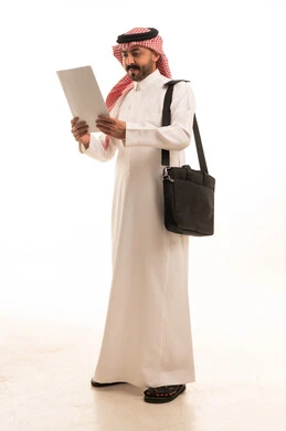رجل سعودي بالثوب التقليدي يقرأ مستند رسمي