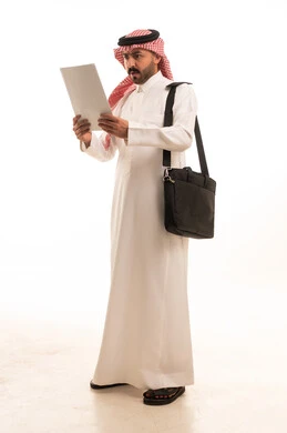 رجل سعودي بالزي التقليدي يقرأ مستنداً