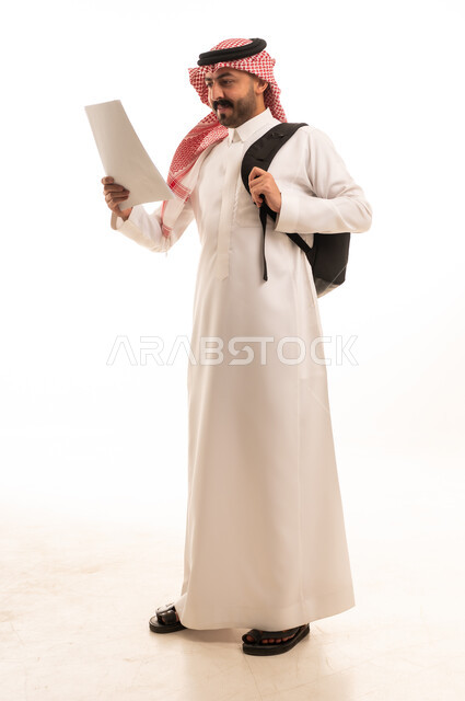 Saudi Man in Thobe with Backpack Reading Document