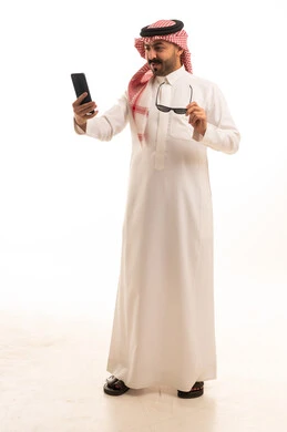 رجل سعودي بالزي التقليدي يستخدم الهاتف الذكي