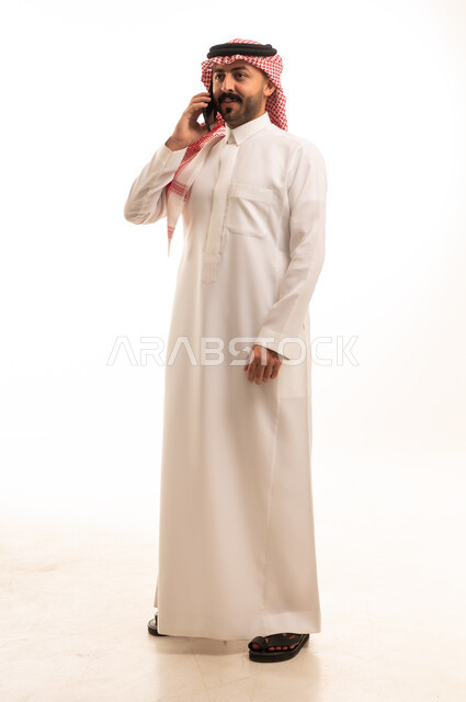 Saudi Man in Traditional Thobe Using Smartphone
