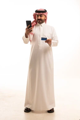 رجل سعودي يحمل هاتفاً ذكياً وبطاقة ائتمان بخلفية بيضاء