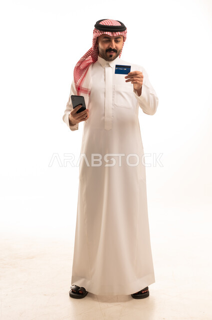 رجل سعودي يمسك بطاقة ائتمان وهاتف ذكي