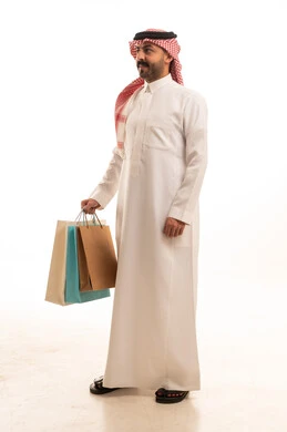 رجل سعودي بالزي التقليدي يحمل أكياس تسوق