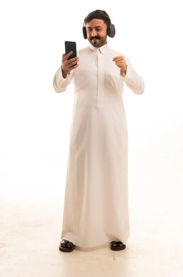 Saudi Man in Thobe Using Headphones and Smartphone
