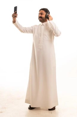 Saudi Man in Thobe Using Smartphone with Headphones