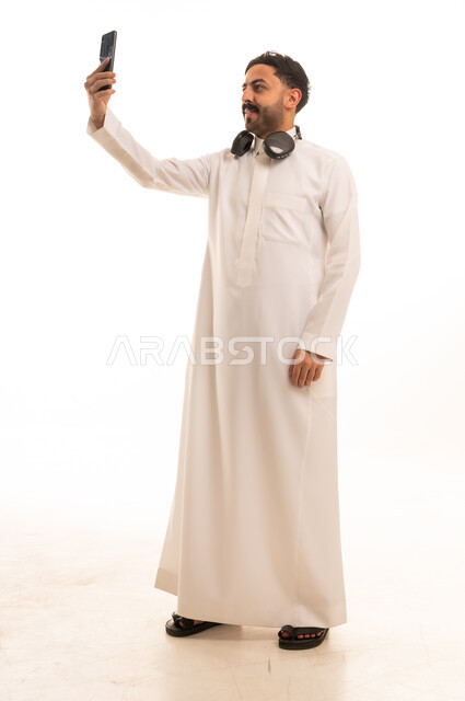رجل سعودي بالثوب التقليدي يلتقط صورة سيلفي بالهاتف