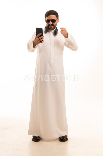 Saudi Man in Traditional Thobe Using Smartphone Studio