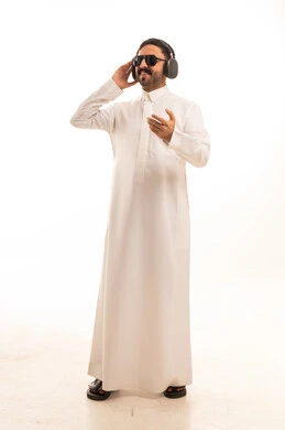 رجل سعودي بالثوب الأبيض يرتدي سماعات ونظارات شمسية