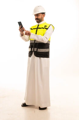 مهندس سعودي يرتدي سترة السلامة ويستخدم الهاتف