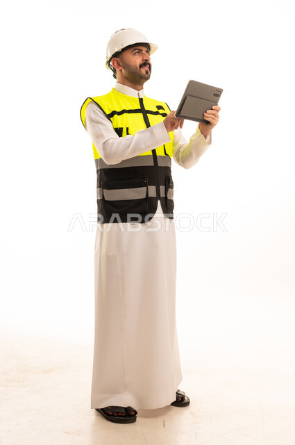 مهندس سعودي بزي السلامة يمسك جهازاً لوحياً