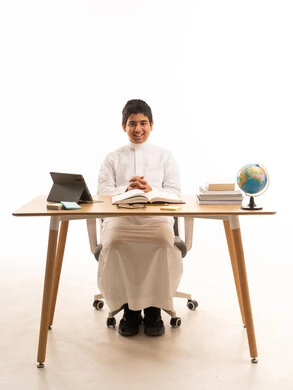 Saudi Boy Student in Traditional Thobe at Study Desk