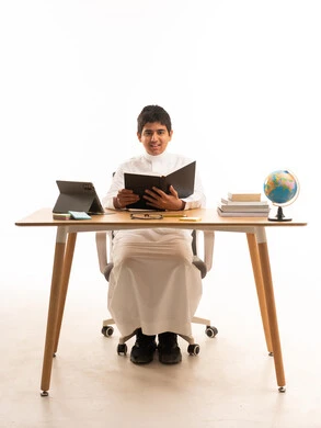 Saudi Student in Traditional Thobe Studying at Desk