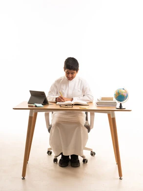 طالب سعودي يدرس على المكتب بالثوب التقليدي