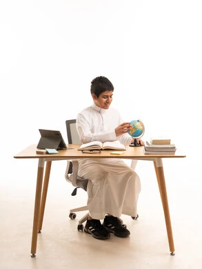 Saudi Boy in Traditional Thobe Studying with World Globe